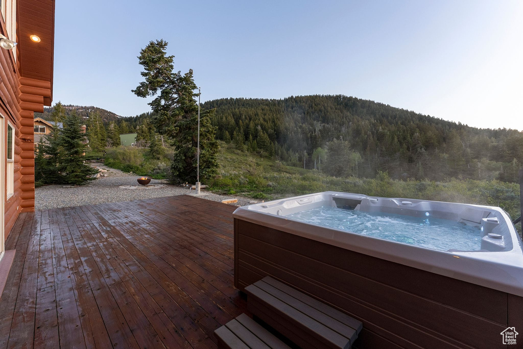 Wooden deck featuring a forest view, a hot tub, and a mountain view