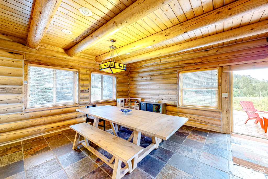 Dining space with wooden ceiling with exposed beams and stone tile flooring