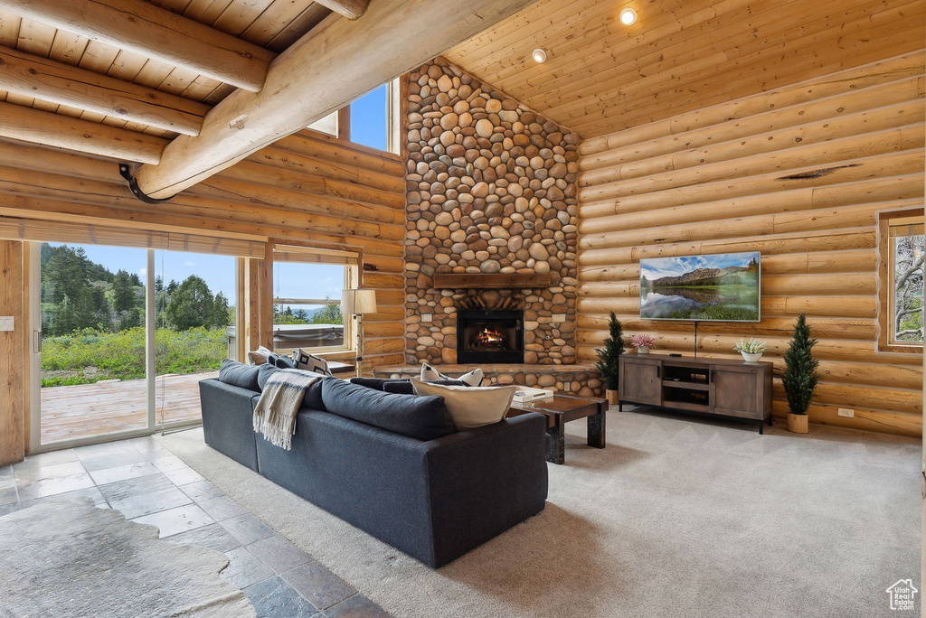 Living room featuring wooden ceiling with exposed beams, high vaulted ceiling, a stone fireplace, rustic walls, and stone tile floors