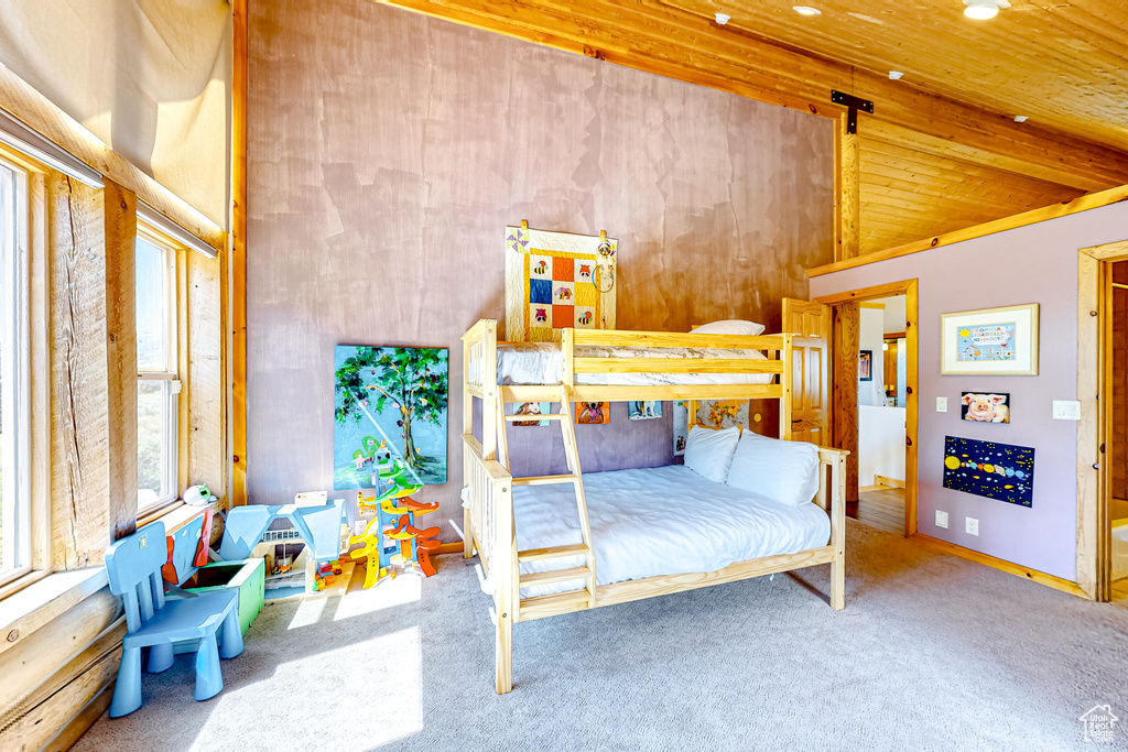 Carpeted bedroom with high vaulted ceiling and wood ceiling