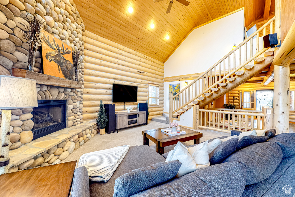 Living area with high vaulted ceiling, wooden ceiling, stairs, log walls, and ceiling fan
