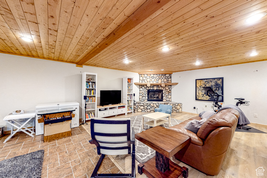 Living area featuring a fireplace, wood ceiling, recessed lighting, baseboards, and stone tile floors