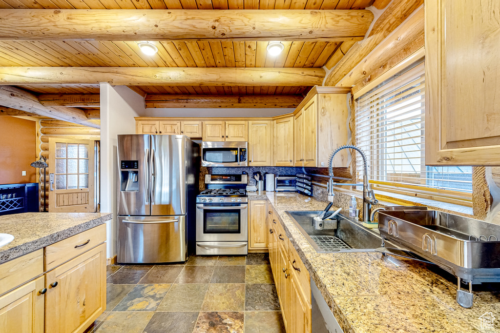 Kitchen featuring stainless steel appliances, light brown cabinets, a sink, wood ceiling with exposed beams, and light countertops