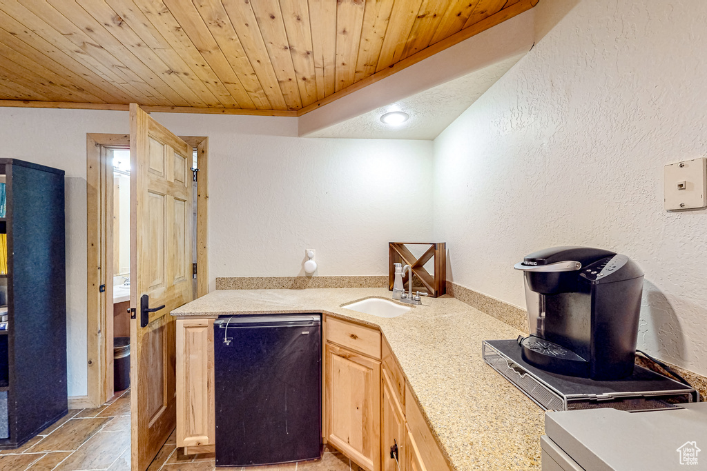 Kitchen featuring a sink, light countertops, light brown cabinetry, wooden ceiling, and dishwasher