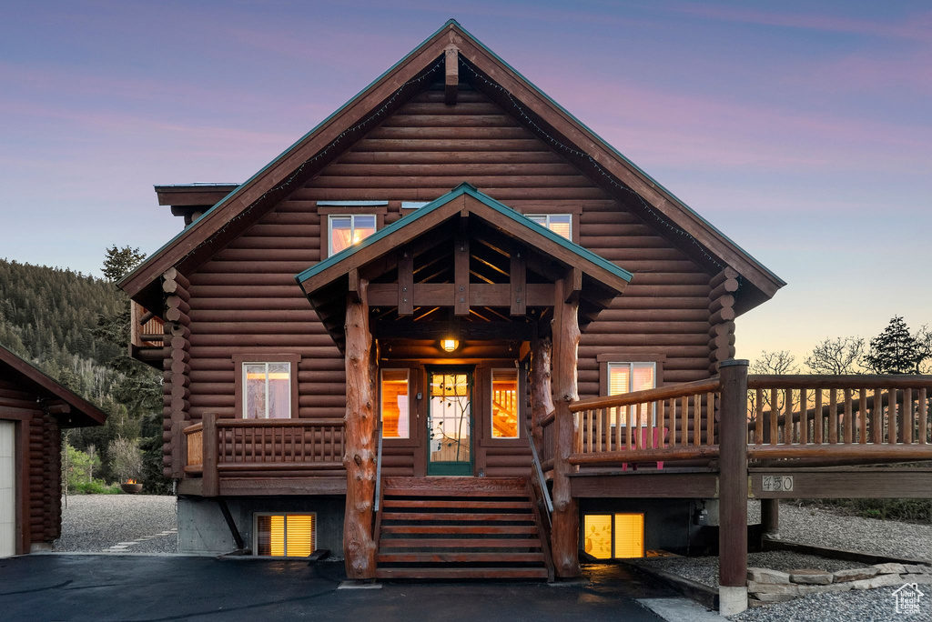 Log-style house with log exterior, covered porch, and stairs
