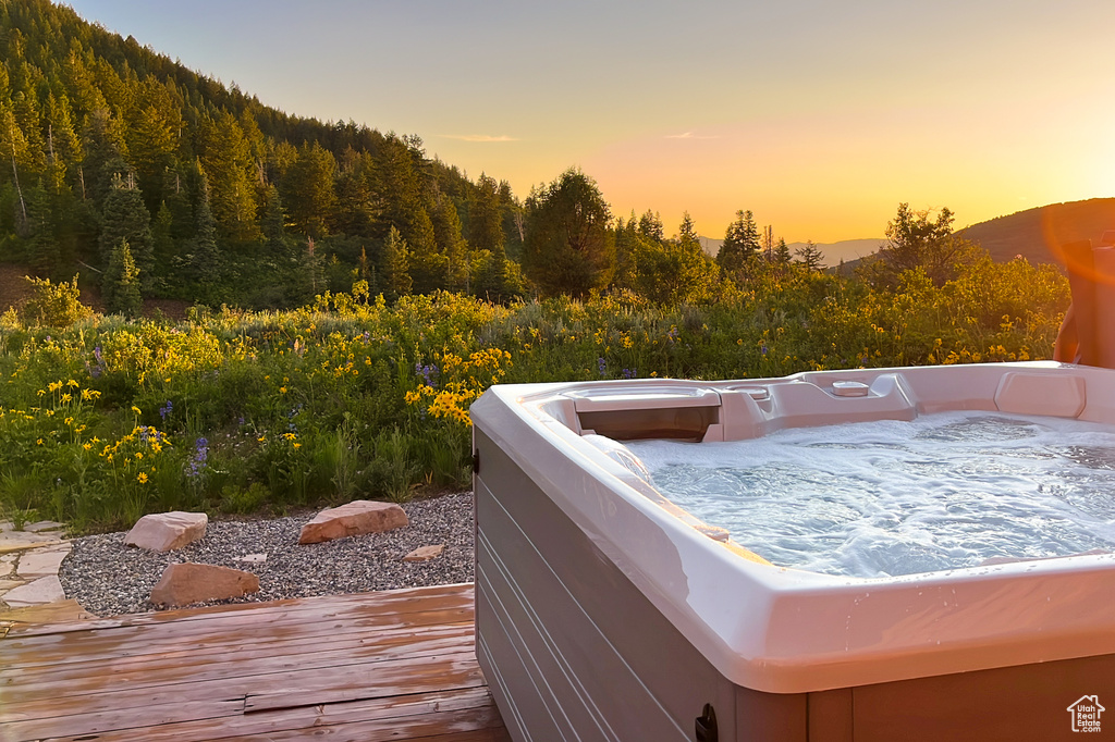 Wooden terrace featuring a hot tub and a view of trees