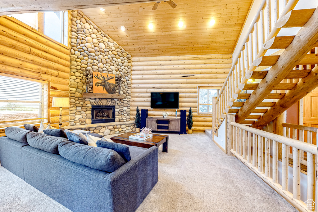 Carpeted living room with plenty of natural light, rustic walls, wooden ceiling, high vaulted ceiling, and a stone fireplace
