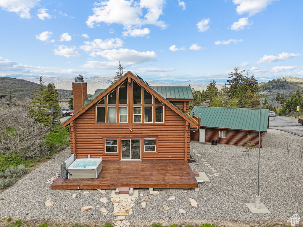 Rear view of house featuring log siding, a chimney, a deck with mountain view, and metal roof