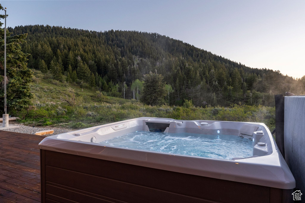 Wooden terrace featuring a view of trees, a hot tub, and a mountain view