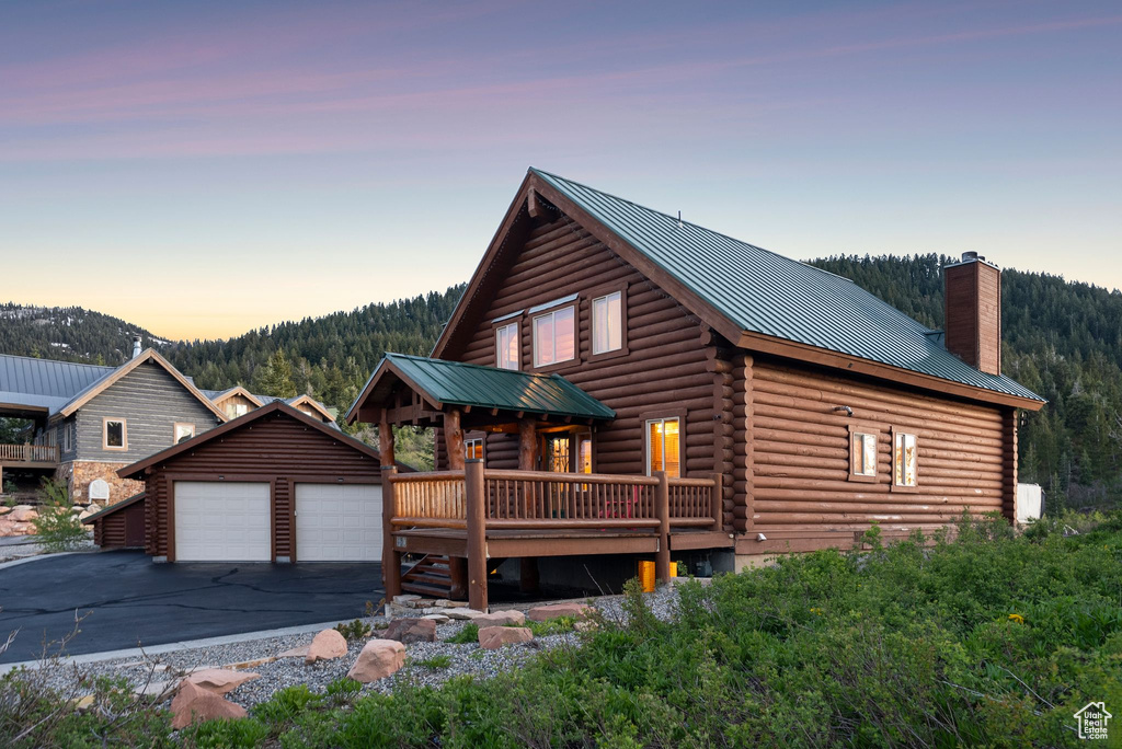 Log-style house featuring an outdoor structure, log exterior, a chimney, metal roof, and a deck