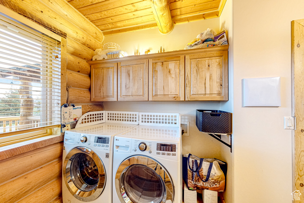 Laundry room with rustic walls, cabinet space, washer and dryer, and wooden ceiling