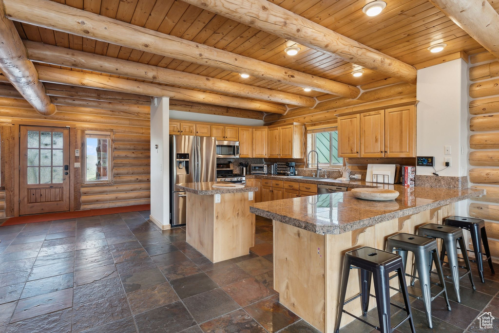Kitchen featuring appliances with stainless steel finishes, wood ceiling with exposed beams, tile countertops, a sink, and a peninsula