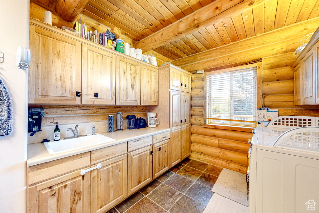 Laundry room with cabinet space, washer and dryer, log walls, wooden ceiling, and dark stone finish flooring