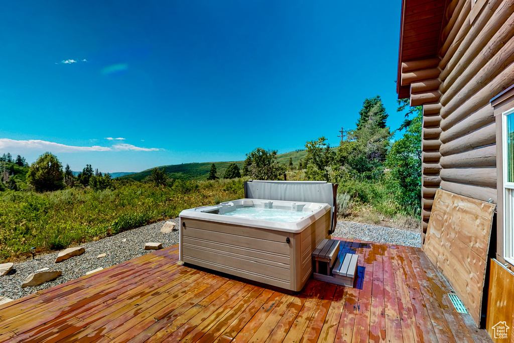 Wooden deck featuring a hot tub and a mountain view