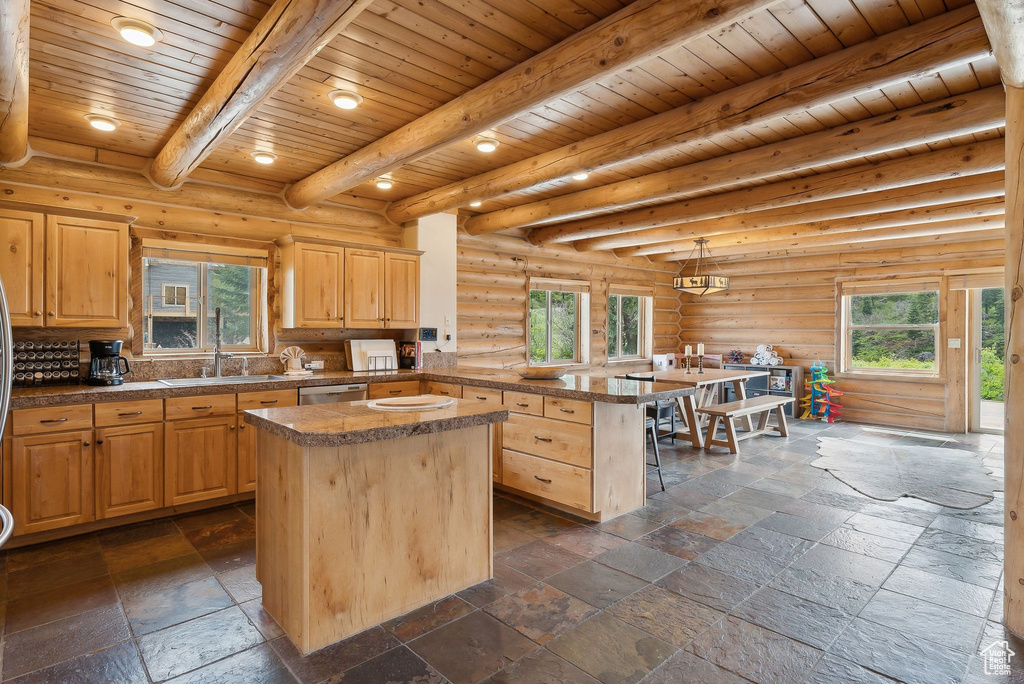 Kitchen with a sink, a kitchen island, light brown cabinets, a peninsula, and wooden ceiling with exposed beams