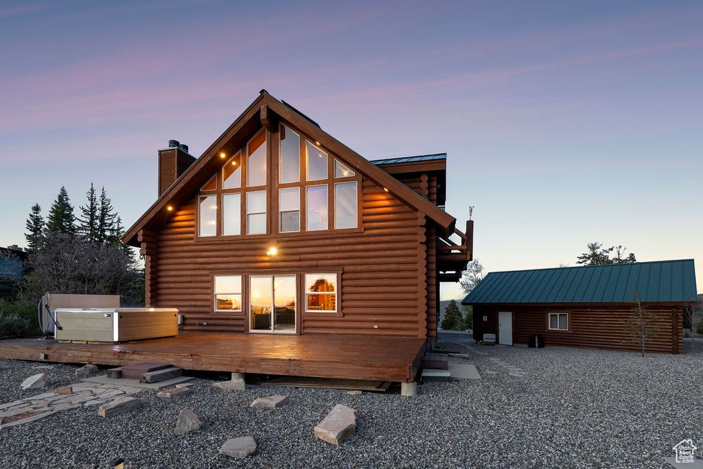 Rear view of property with log exterior, a chimney, a wooden deck, and metal roof