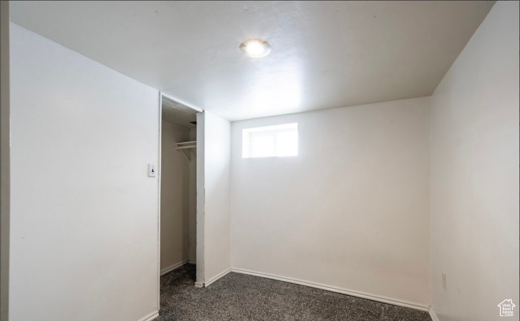 Unfurnished bedroom featuring dark colored carpet, a closet, and baseboards
