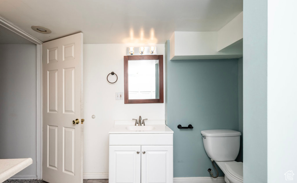 Bathroom featuring toilet, vanity, and baseboards
