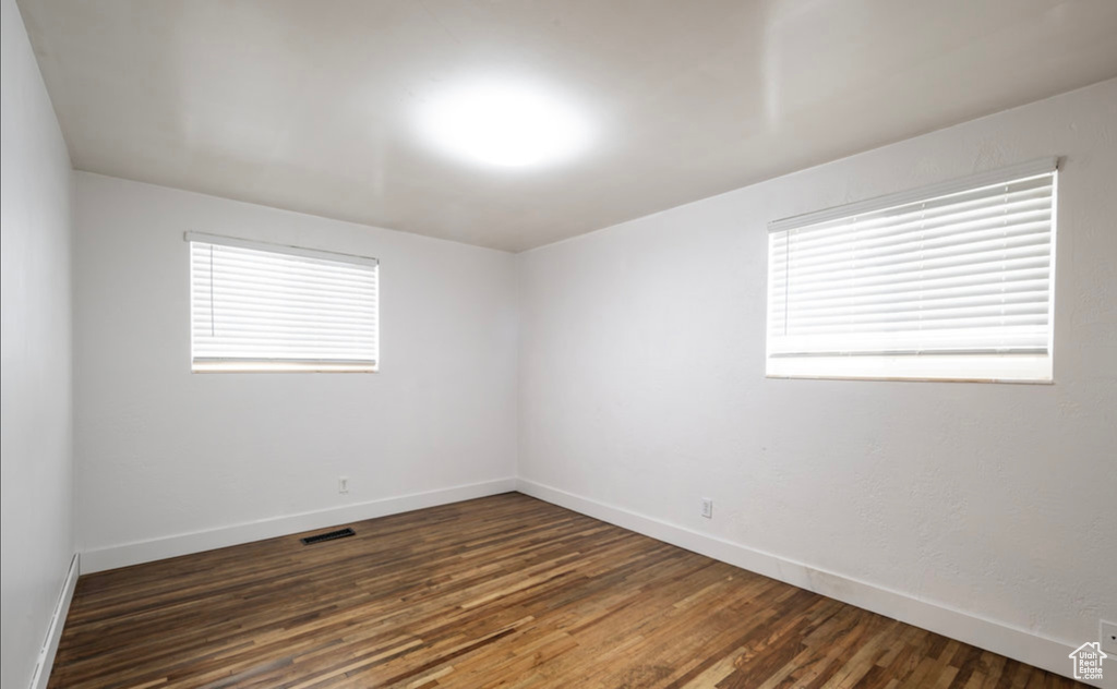 Empty room featuring plenty of natural light, baseboards, and dark wood-type flooring