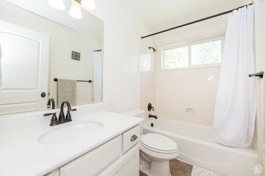 Bathroom with toilet, shower / bath combo, and vanity