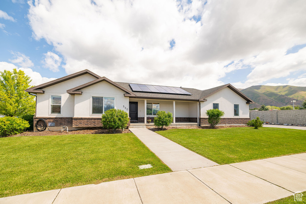 Ranch-style home with brick siding, a porch, solar panels, and stucco siding