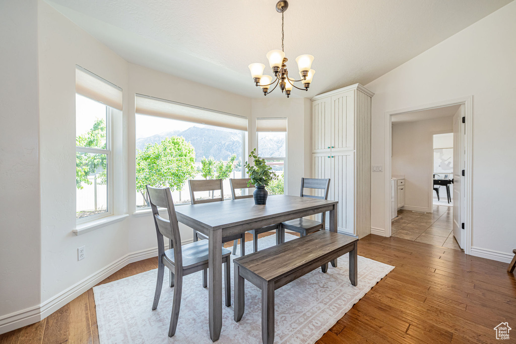 Dining room with a chandelier, baseboards, a mountain view, light wood-style flooring, and lofted ceiling