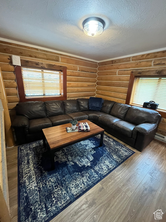 Living room featuring log walls, a textured ceiling, and wood finished floors