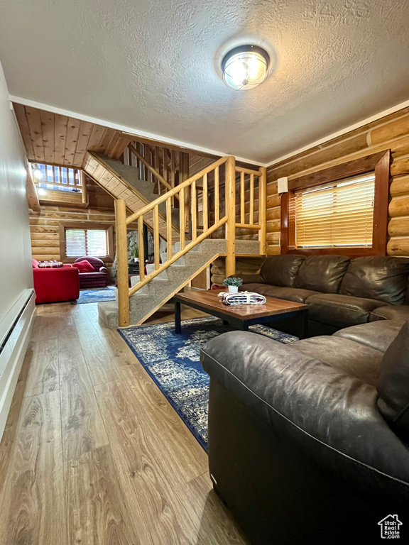Living room with rustic walls, wood-type flooring, stairway, and a textured ceiling