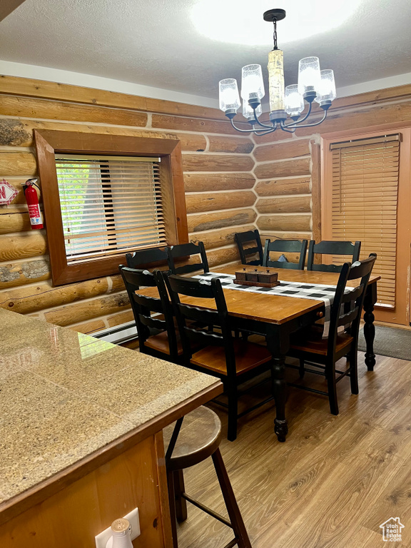Dining area featuring log walls, a chandelier, and light wood finished floors