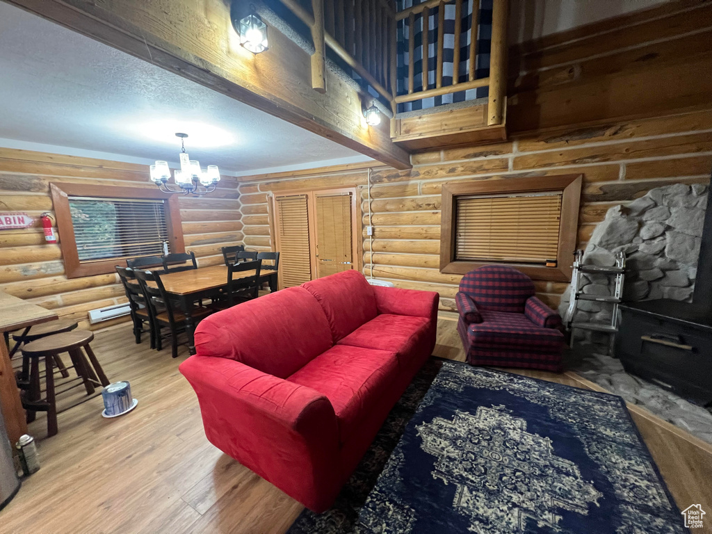 Living area featuring a chandelier, log walls, wood finished floors, and a baseboard radiator