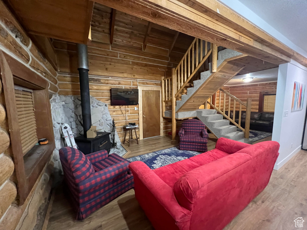Living room with stairs, a wood stove, and wood finished floors