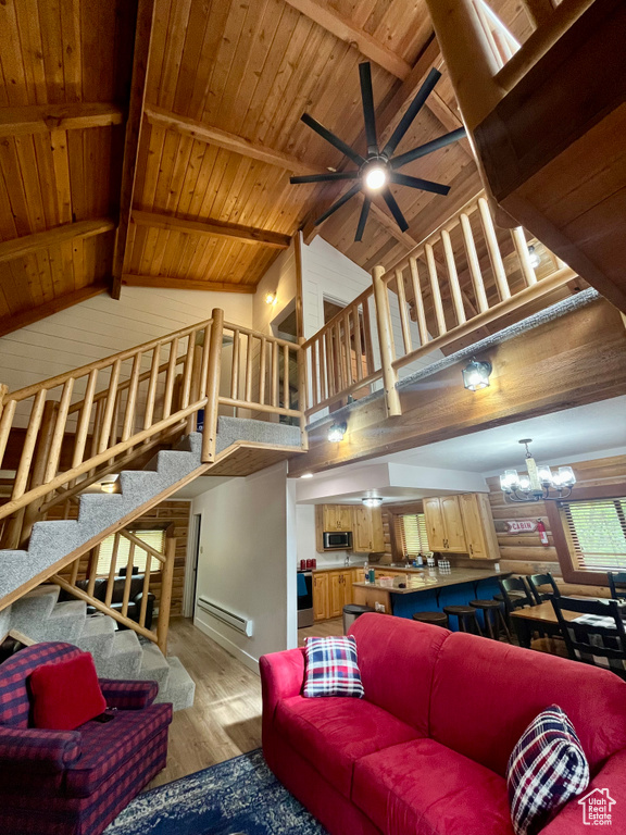 Living area featuring high vaulted ceiling, light wood-style flooring, a ceiling fan, a chandelier, and wood ceiling with exposed beams