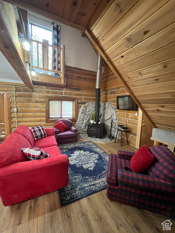 Living room with a wood stove, vaulted ceiling, wooden ceiling, log walls, and wood finished floors