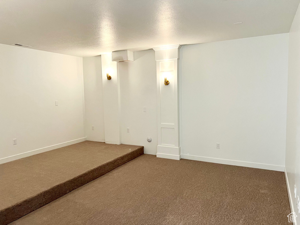Spare room with carpet, a textured ceiling, and baseboards
