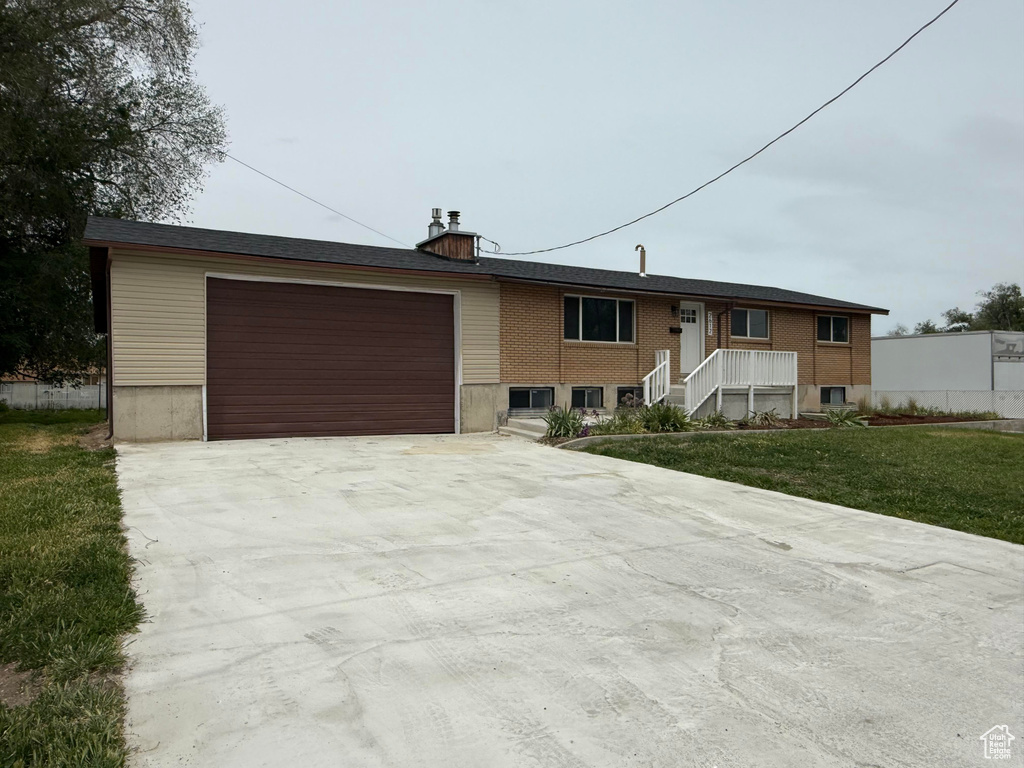 View of front facade with driveway, a front lawn, and a garage