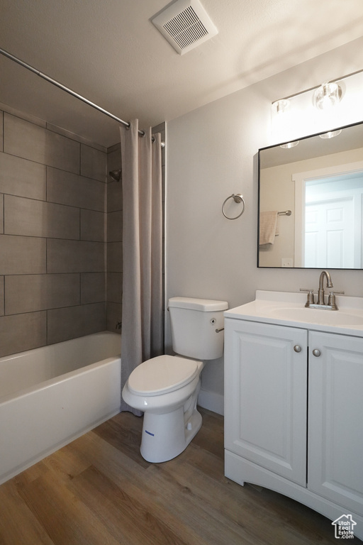 Bathroom featuring wood finished floors, toilet, vanity, and shower / tub combo