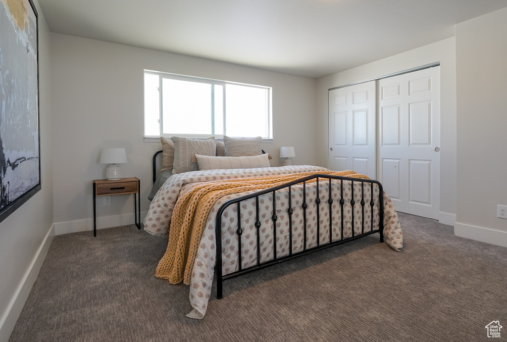 Bedroom with dark colored carpet, a closet, and baseboards