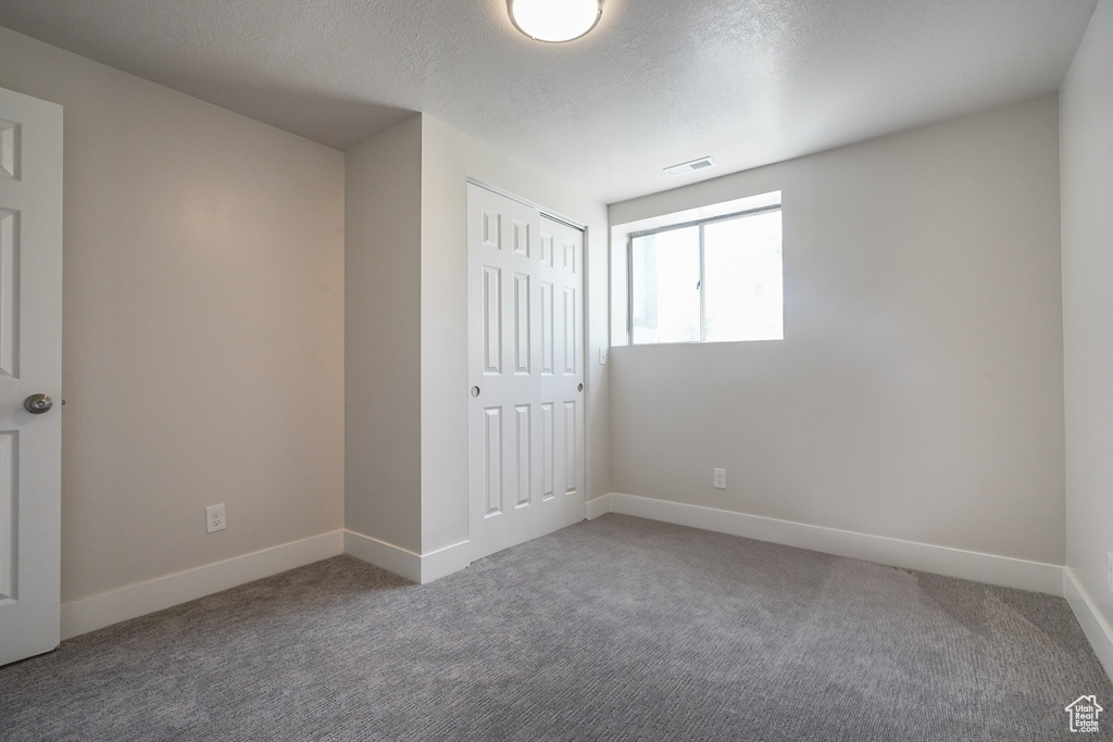 Unfurnished bedroom featuring carpet, baseboards, a closet, and a textured ceiling