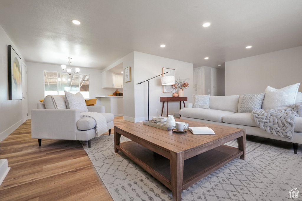 Living room featuring light wood-type flooring, a chandelier, recessed lighting, and baseboards