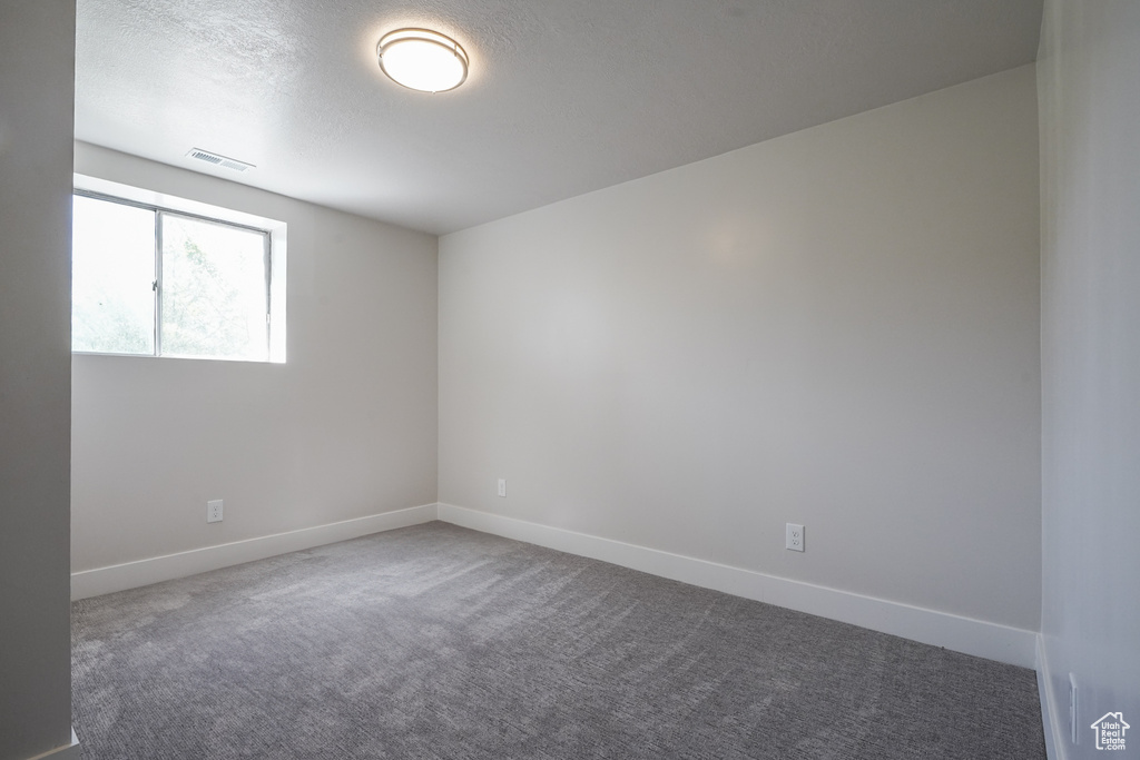Unfurnished room featuring carpet floors, baseboards, and a textured ceiling