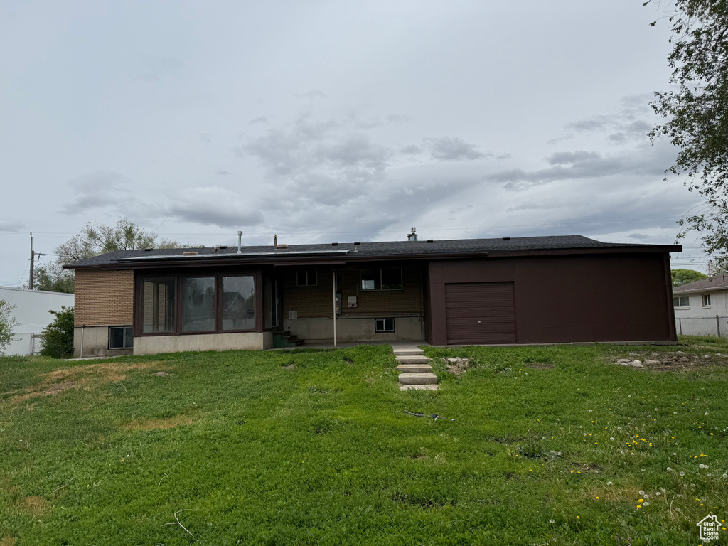 Back of house with a garage, a yard, and a sunroom