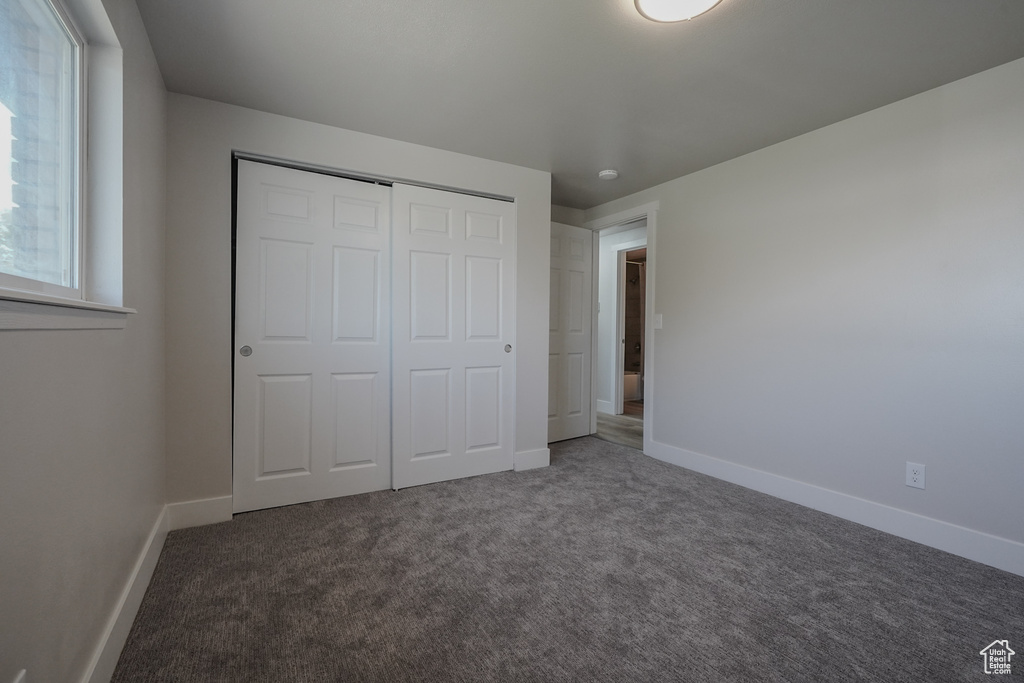 Unfurnished bedroom with carpet floors, a closet, and baseboards
