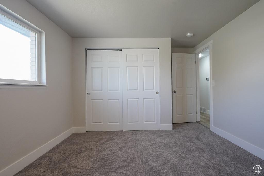 Unfurnished bedroom with carpet floors, a closet, and baseboards