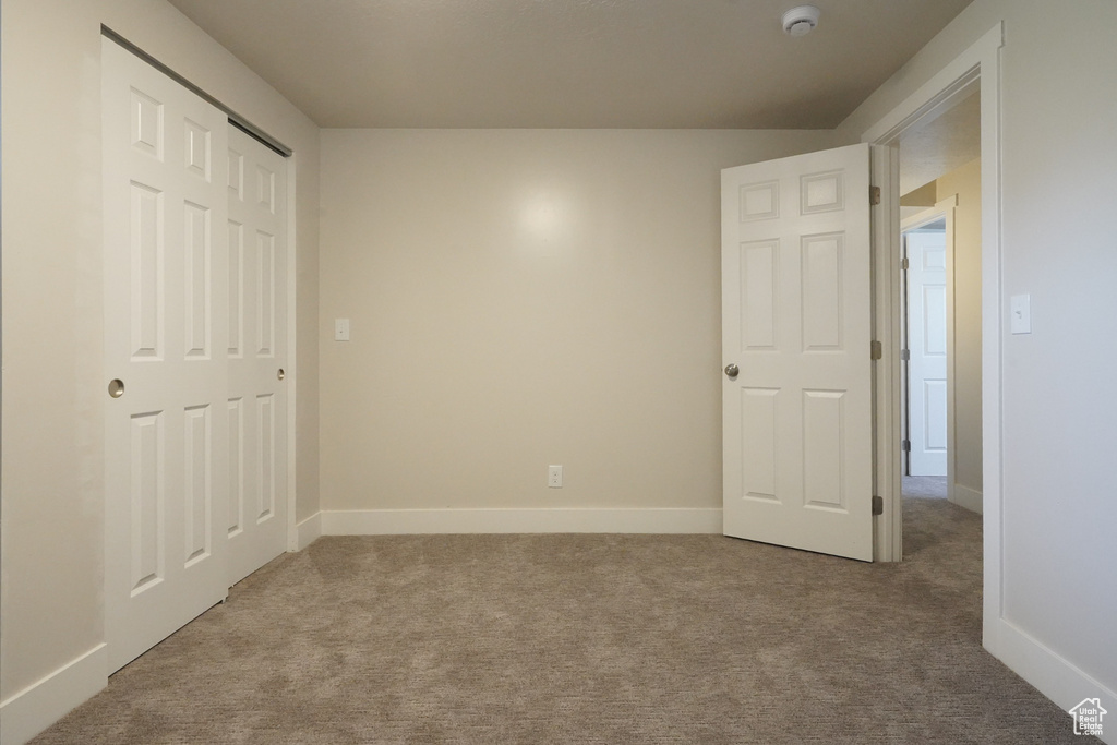 Unfurnished bedroom featuring carpet, baseboards, and a closet