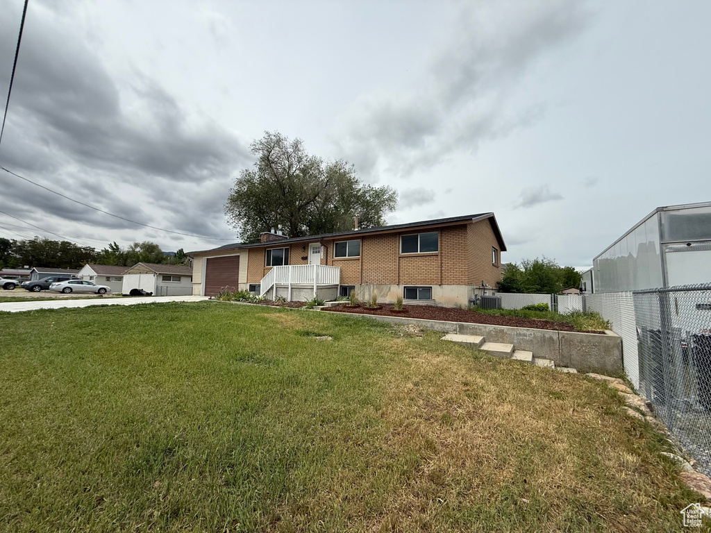 View of front facade featuring a garage, concrete driveway, brick siding, and central air condition unit