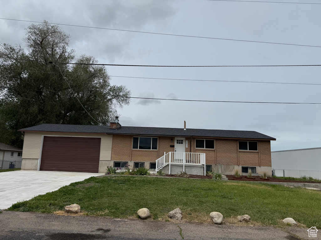 View of front of home featuring concrete driveway, an attached garage, a front lawn, and brick siding