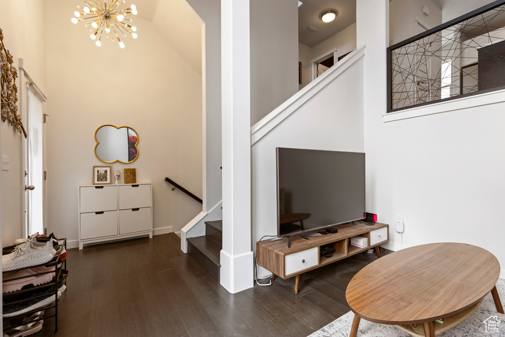 Living area featuring stairway, wood finished floors, a towering ceiling, and a chandelier