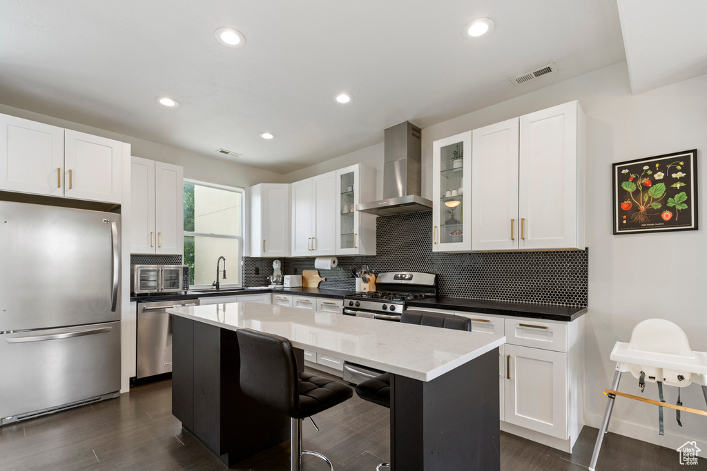 Kitchen with appliances with stainless steel finishes, wall chimney exhaust hood, decorative backsplash, a center island, and recessed lighting