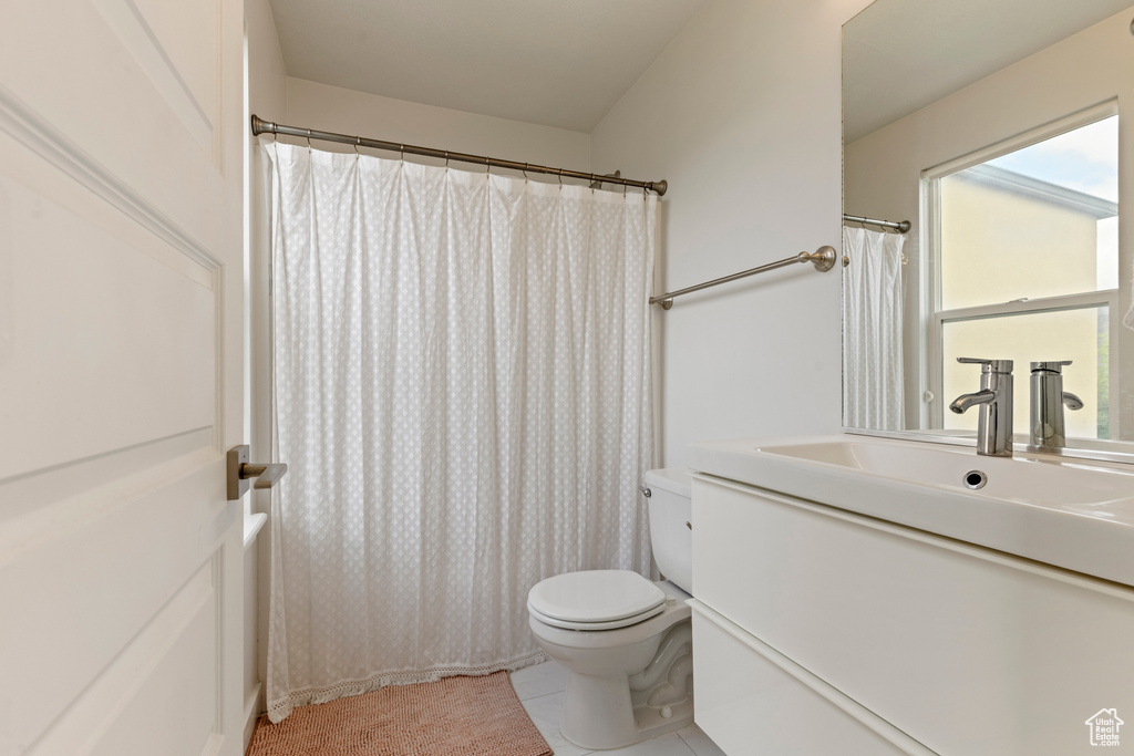 Bathroom with toilet, vanity, tile patterned floors, and a shower with curtain