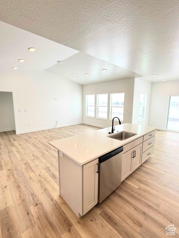 Kitchen with dishwasher, open floor plan, a sink, light wood-type flooring, and a textured ceiling
